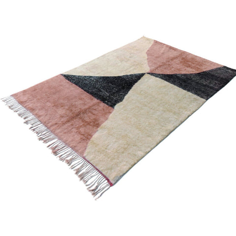 Lifestyle shot of the pink Moroccan rug in a natural setting, featuring geometric patterns and fringed edges.