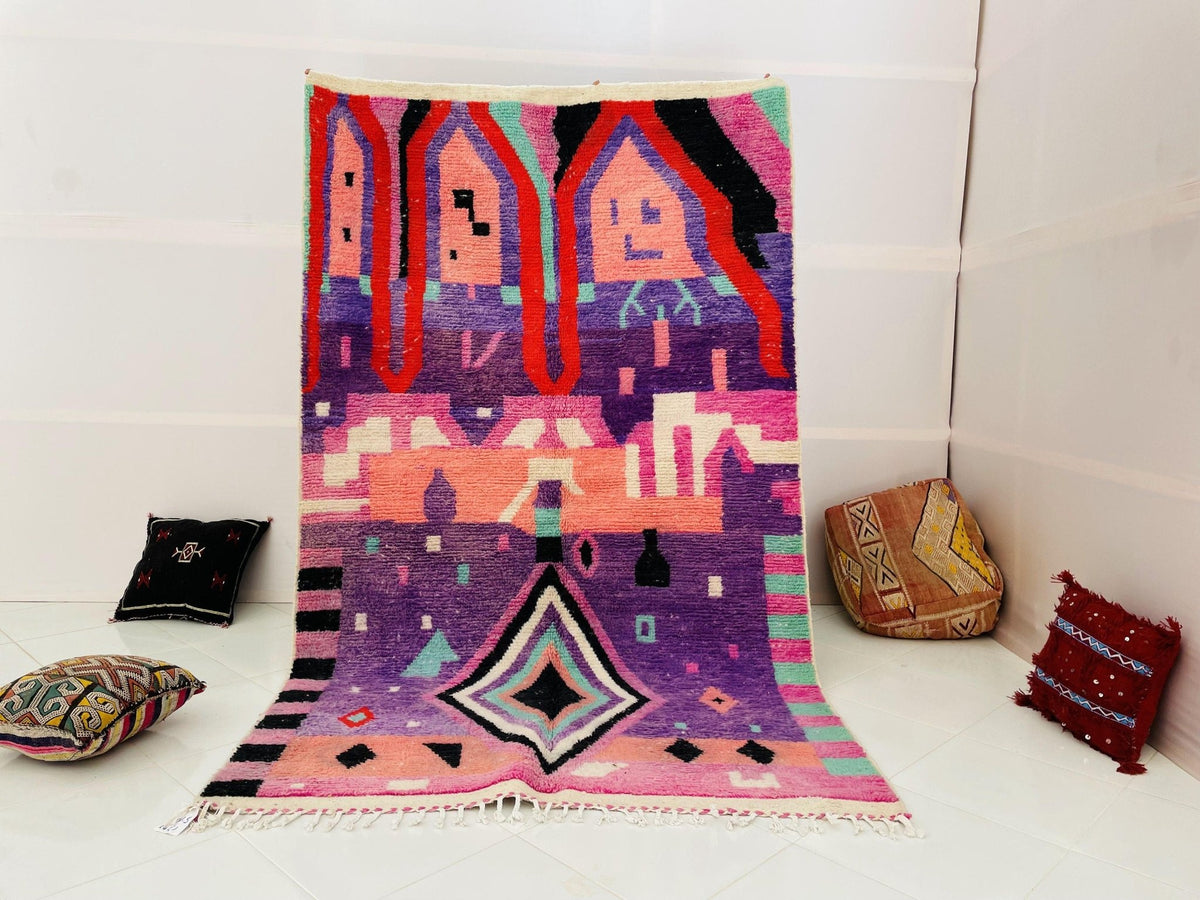 Lifestyle shot of a purple and pink patterned Moroccan rug on a white background.