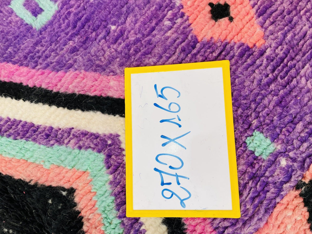 Detail shot of unique shapes and bold colors on a purple and pink patterned Moroccan rug.