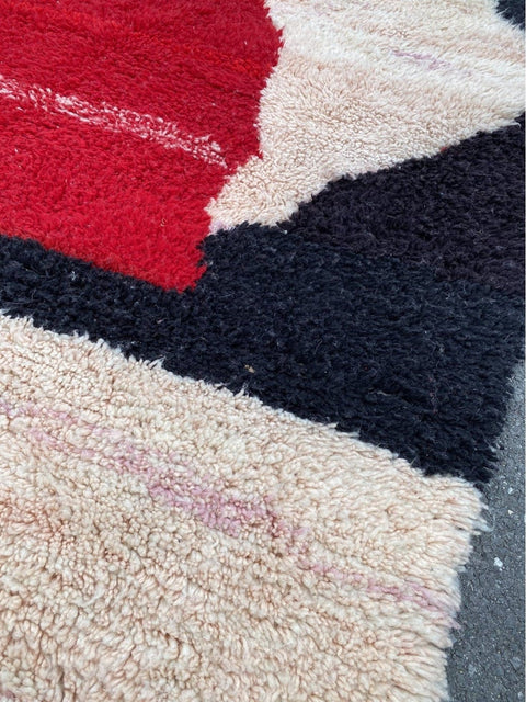 Front view showcasing the red and black rug with fringed edges and thick pile.