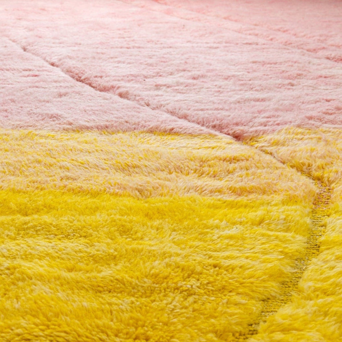 Close-up detail of the rose and yellow rug highlighting its soft texture and color gradient.