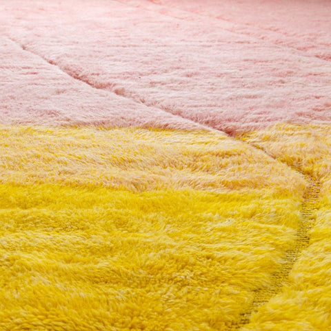 Close-up detail of the rose and yellow rug highlighting its soft texture and color gradient.