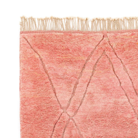 Close-up detail of the rose and yellow rug featuring a geometric pattern and soft texture.