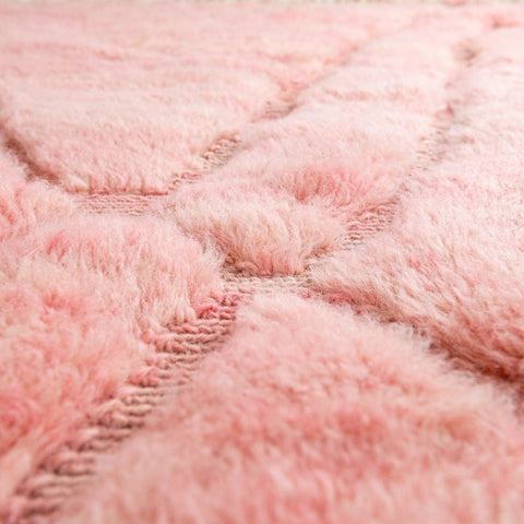 Close-up detail of the texture of the rose and yellow carpet rug with woven pattern.