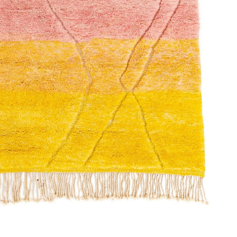 Close-up detail of the rose and yellow rug showcasing fringe edges and soft texture.