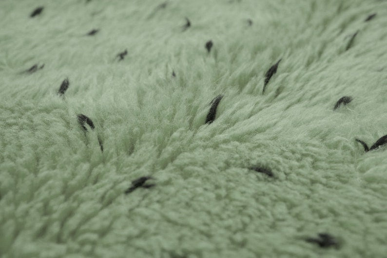 Detail close-up of sage green rug with white dots pattern.