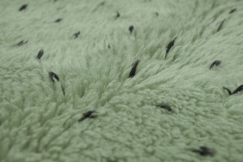 Detail close-up of sage green rug with white dots pattern.