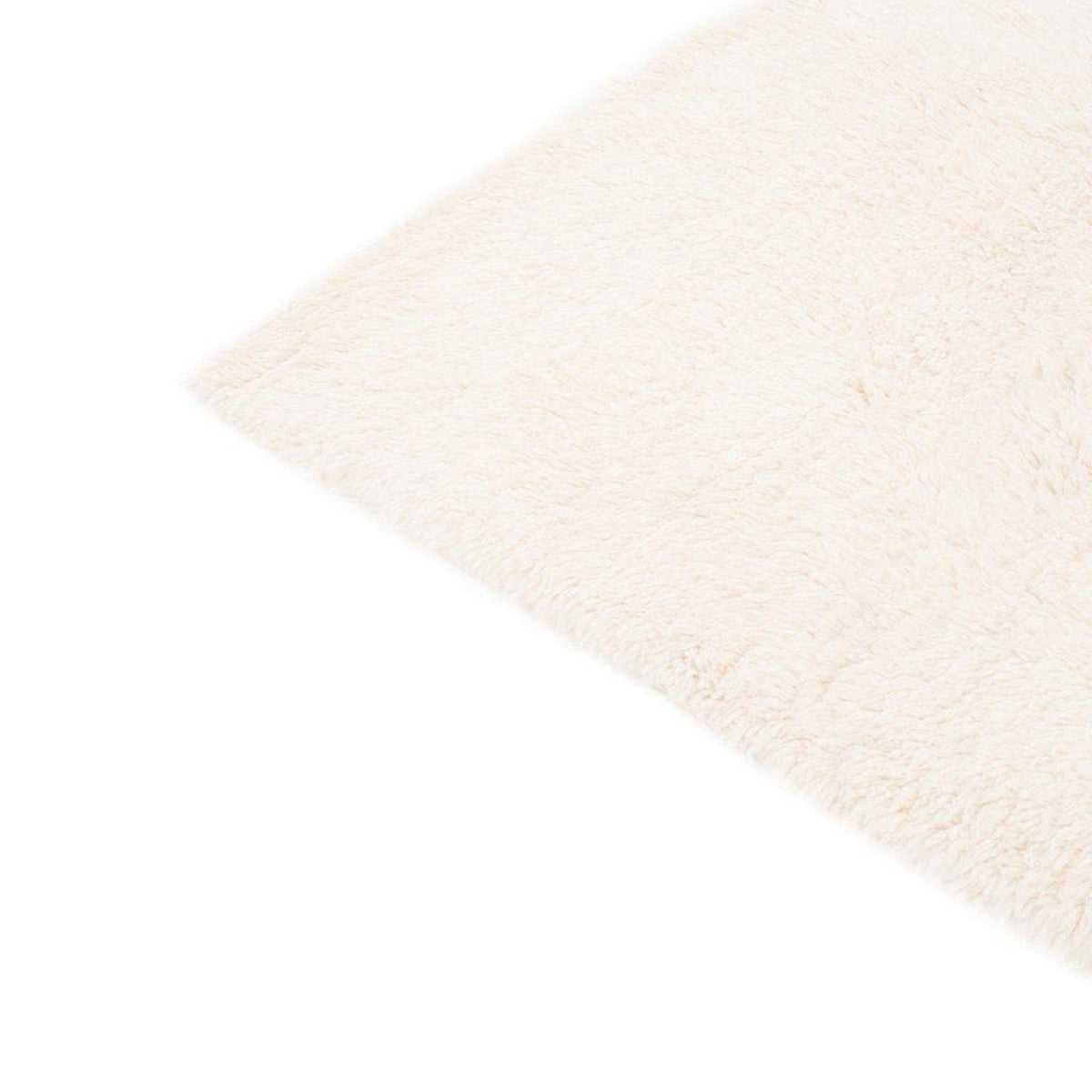 Side view of the cream and gray rug displaying the diamond pattern and fringed edges.
