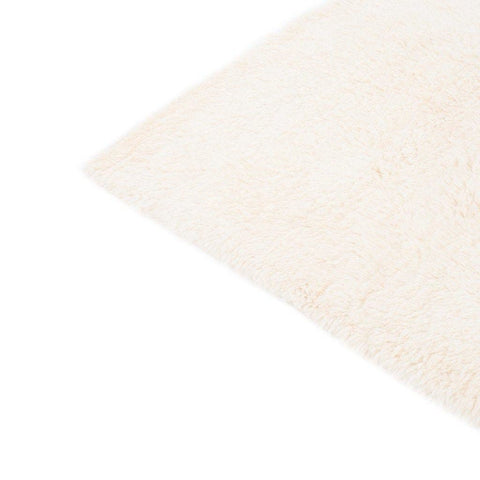 Side view of the cream and gray rug displaying the diamond pattern and fringed edges.