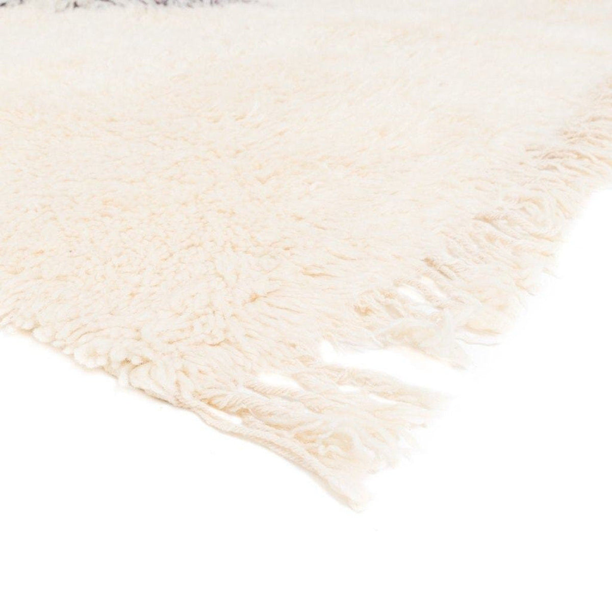 Detail close-up of the cream rug with fringed edges against a white background.