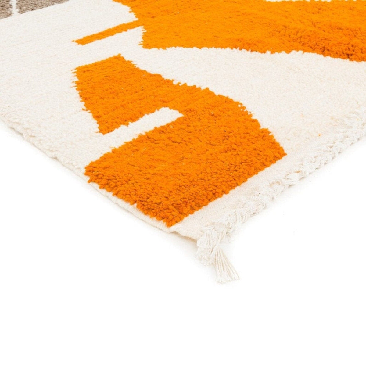 Close-up detail of the textured surface of the orange abstract Moroccan rug with fringe edges.