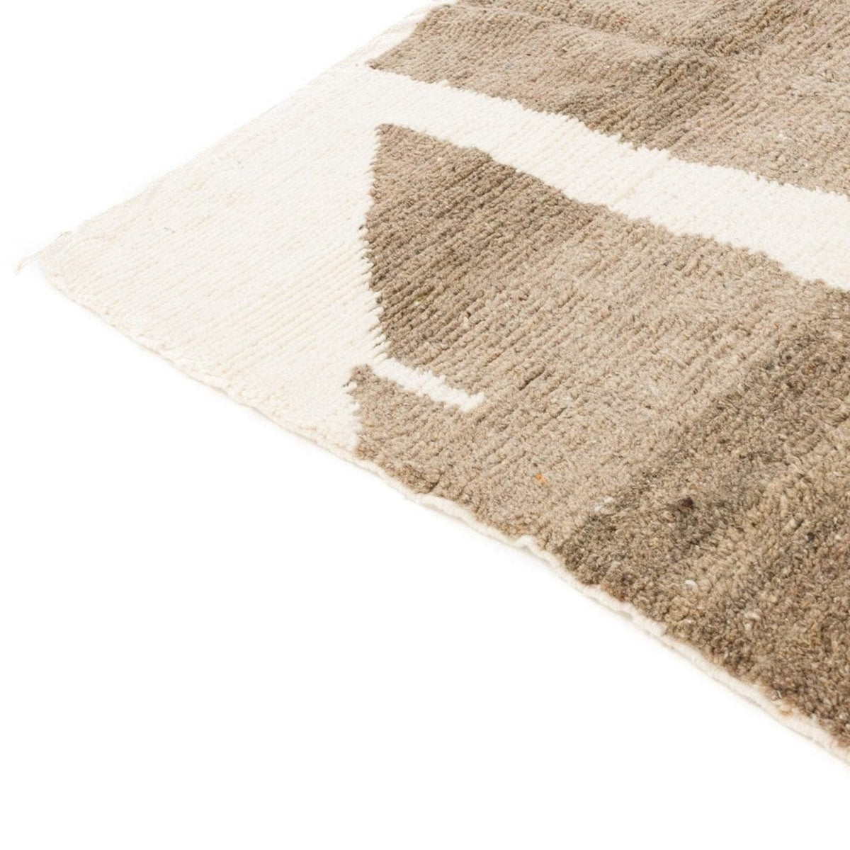 Close-up detail of the edge of the beige abstract Moroccan rug with a fringed edge.