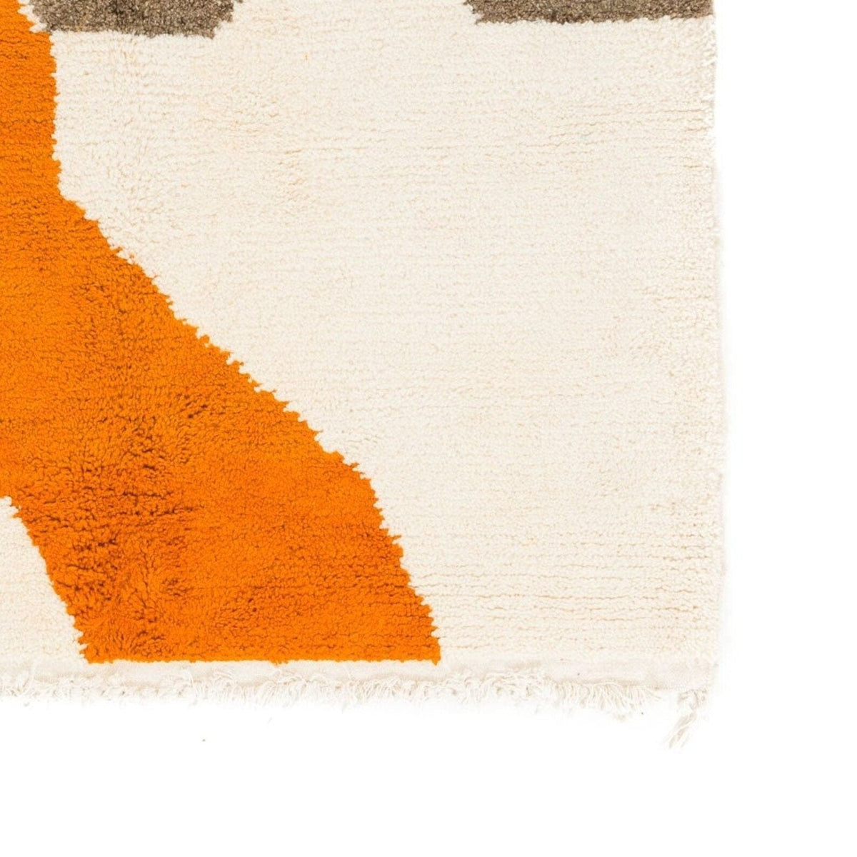 Close-up detail of the corner of the beige abstract Moroccan rug with geometric patterns.