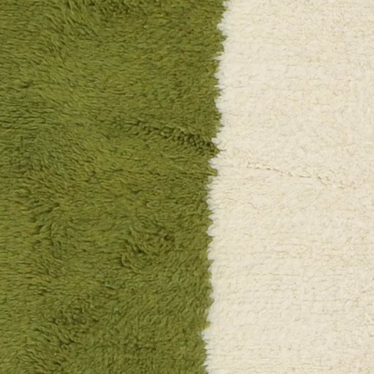 Detail close-up of the orange and green geometric pattern rug with fringe edges.