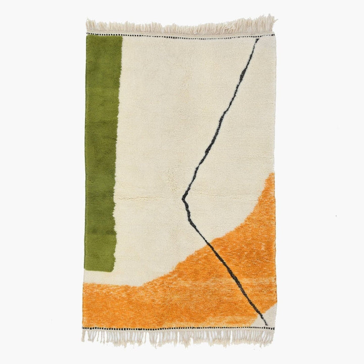 Detail close-up of the orange and green geometric pattern rug with fringe edges.