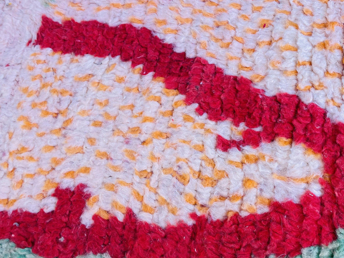 Detail shot of the textured pattern on the Moroccan rug in red, orange, and white.