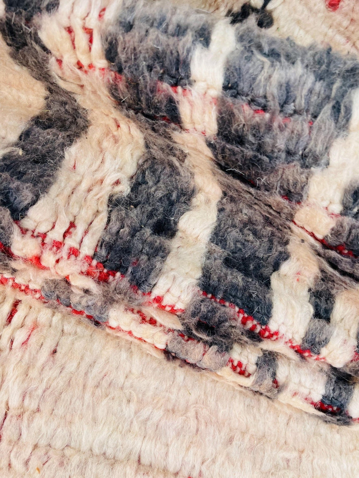 Close-up detail of the rug's woven texture showcasing beige, black, and red colors.