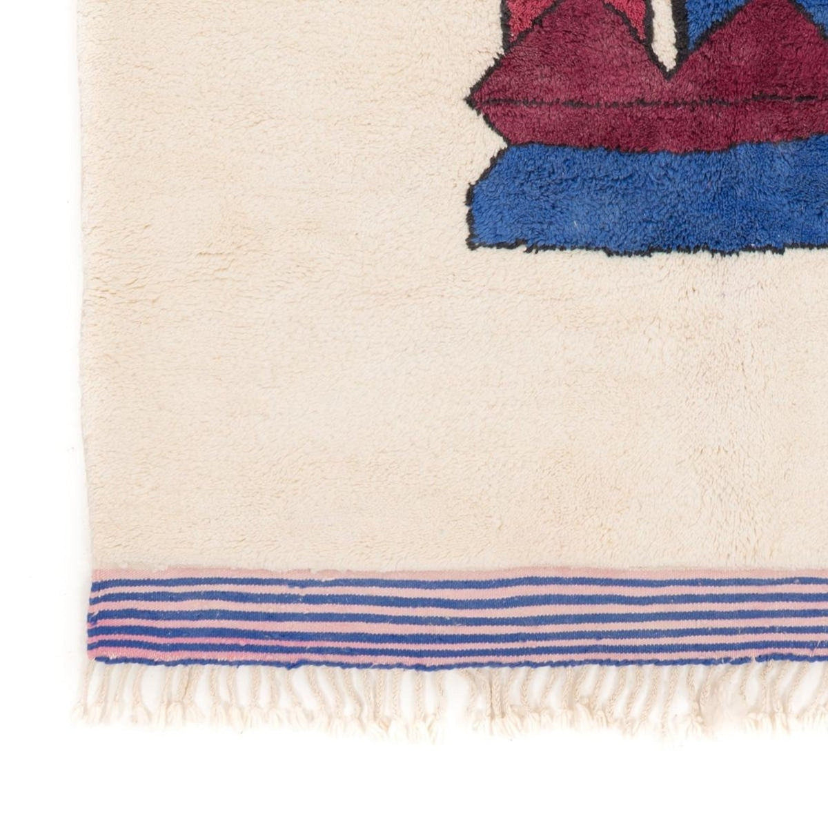 Close-up of the artsy face rug with fringed edge and abstract patterns.
