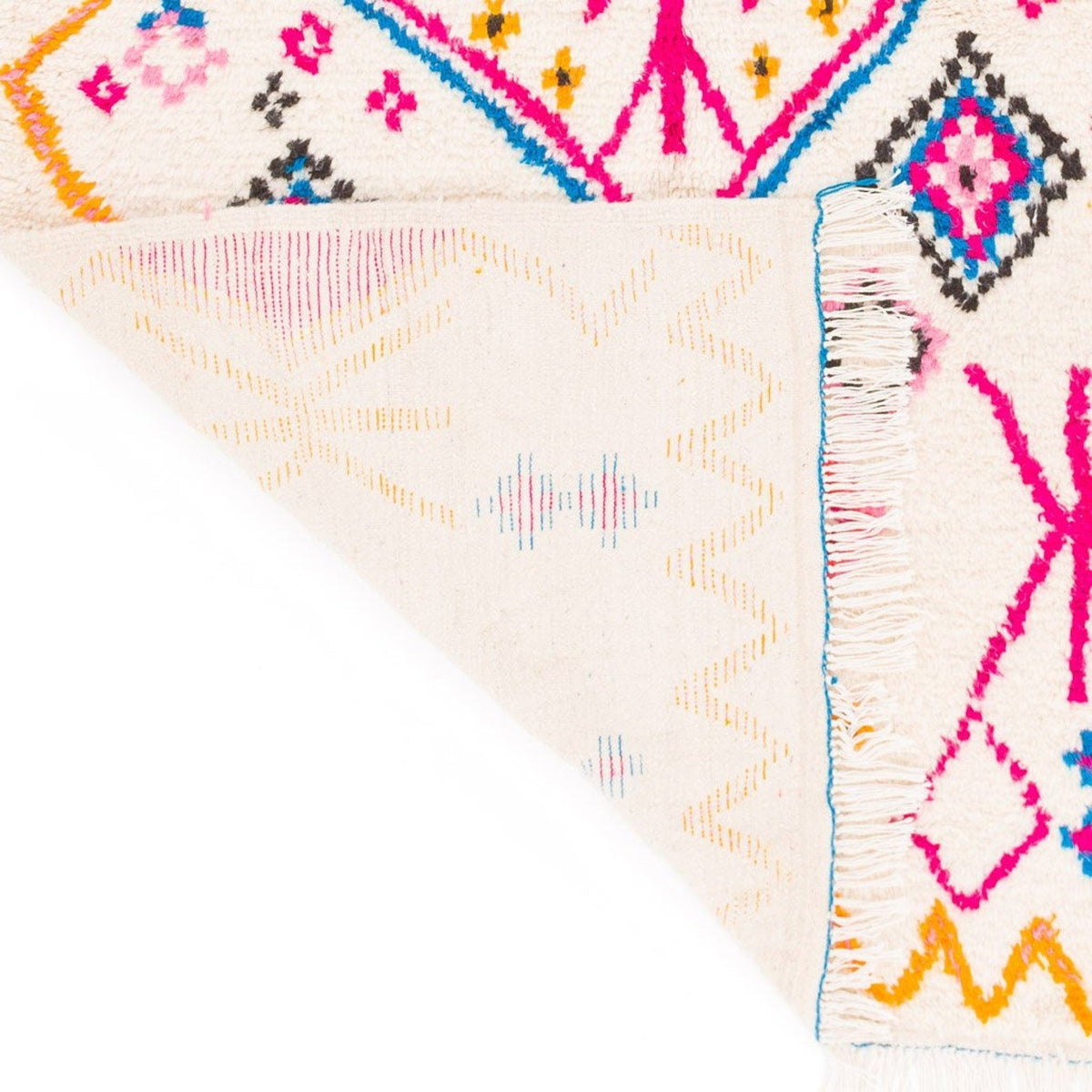 Detail shot of a colorful patterned rug in pink and orange with geometric designs.