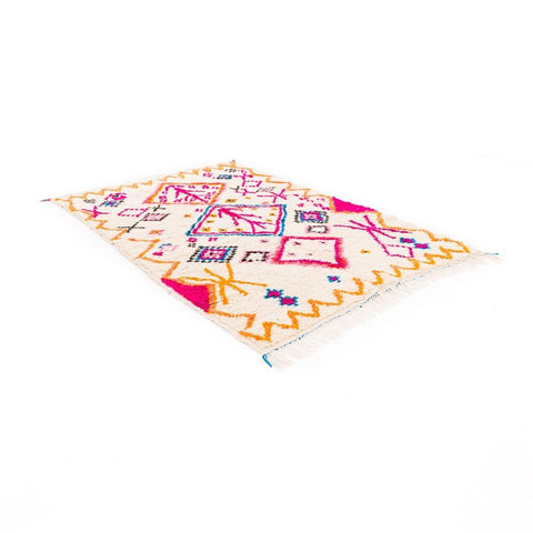 Lifestyle shot of a colorful patterned rug in pink and orange with geometric designs.