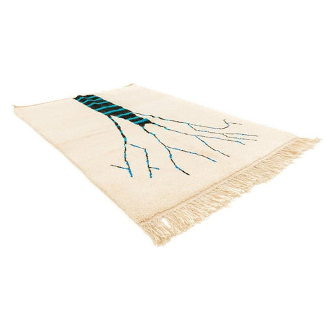 Detail view of the cream tree design rug with fringe edges, showcasing the tree design in cream, blue, and black.