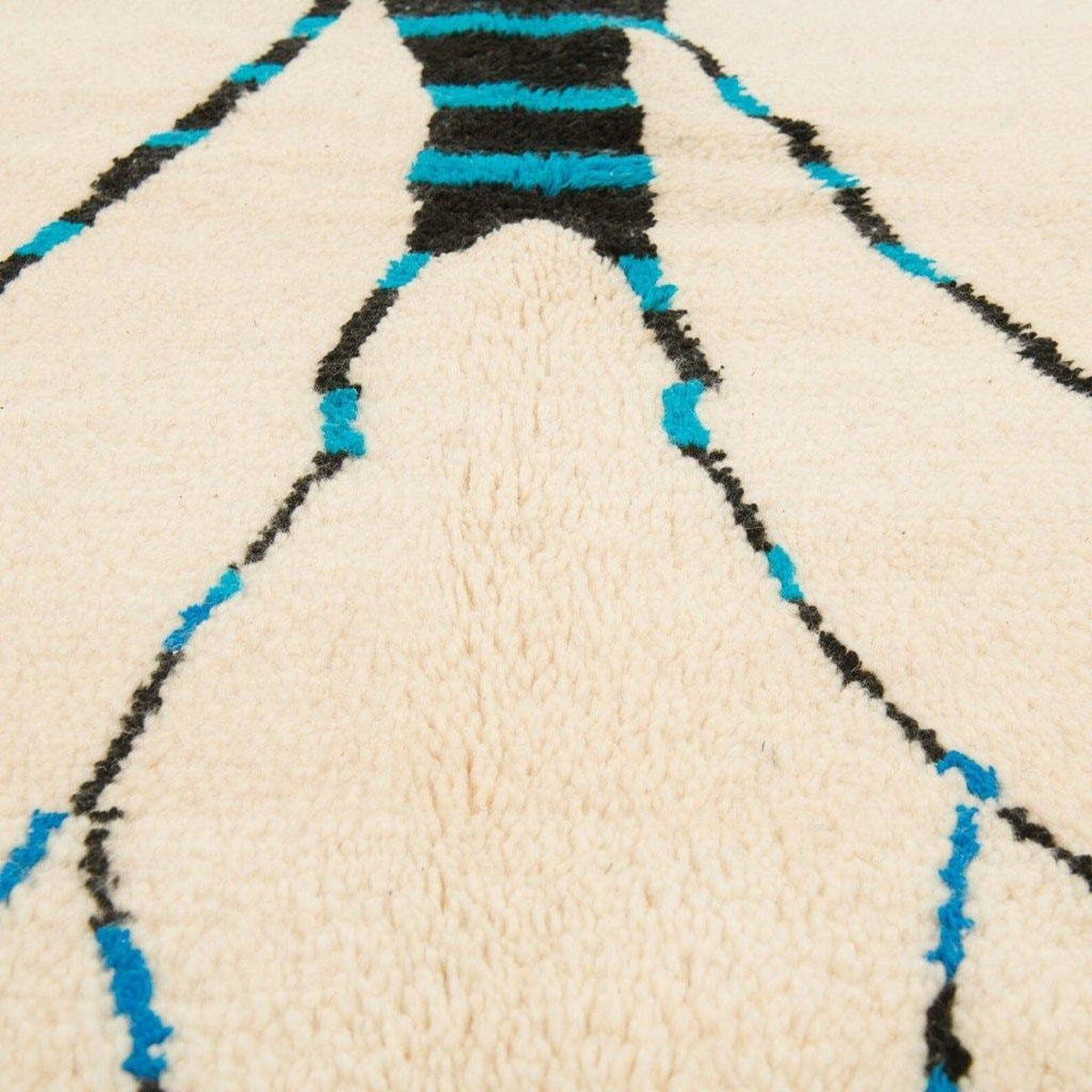 Close-up detail of the cream tree design rug showcasing its abstract patterns in beige, black, and blue.