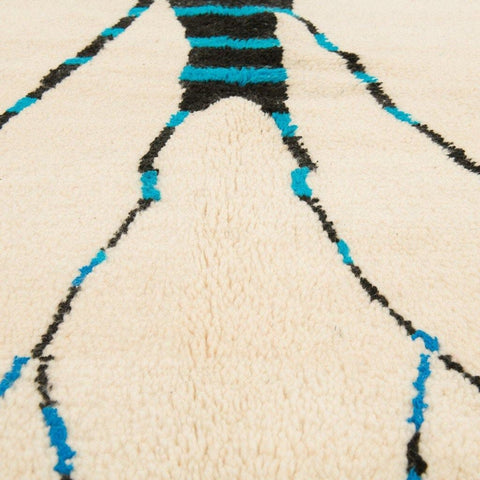 Close-up detail of the cream tree design rug showcasing its abstract patterns in beige, black, and blue.