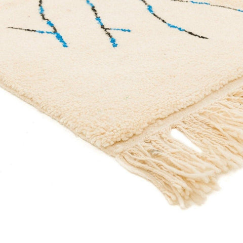 Detail view of the cream tree design rug with fringe edges, featuring abstract patterns in cream, blue, and black.
