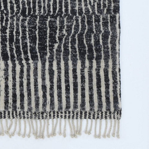 Front view of a black tribal rug showcasing an abstract design and fringe edges.
