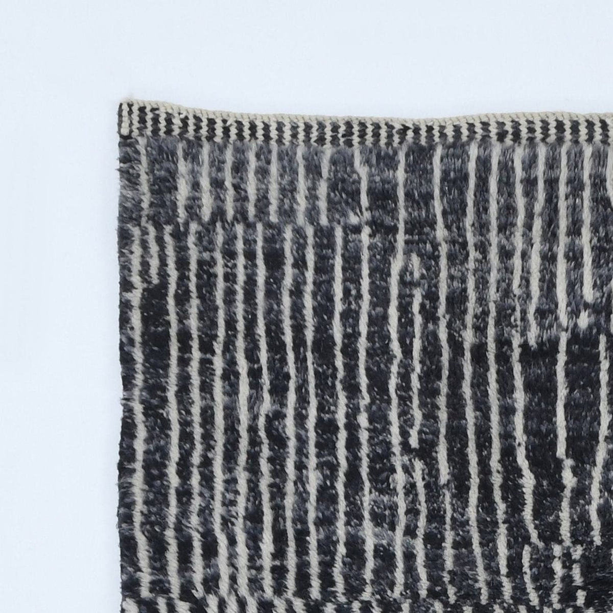 Close-up detail of a black and white rug highlighting a striped pattern and fringe edges.