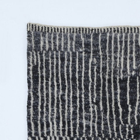 Close-up detail of a black and white rug highlighting a striped pattern and fringe edges.