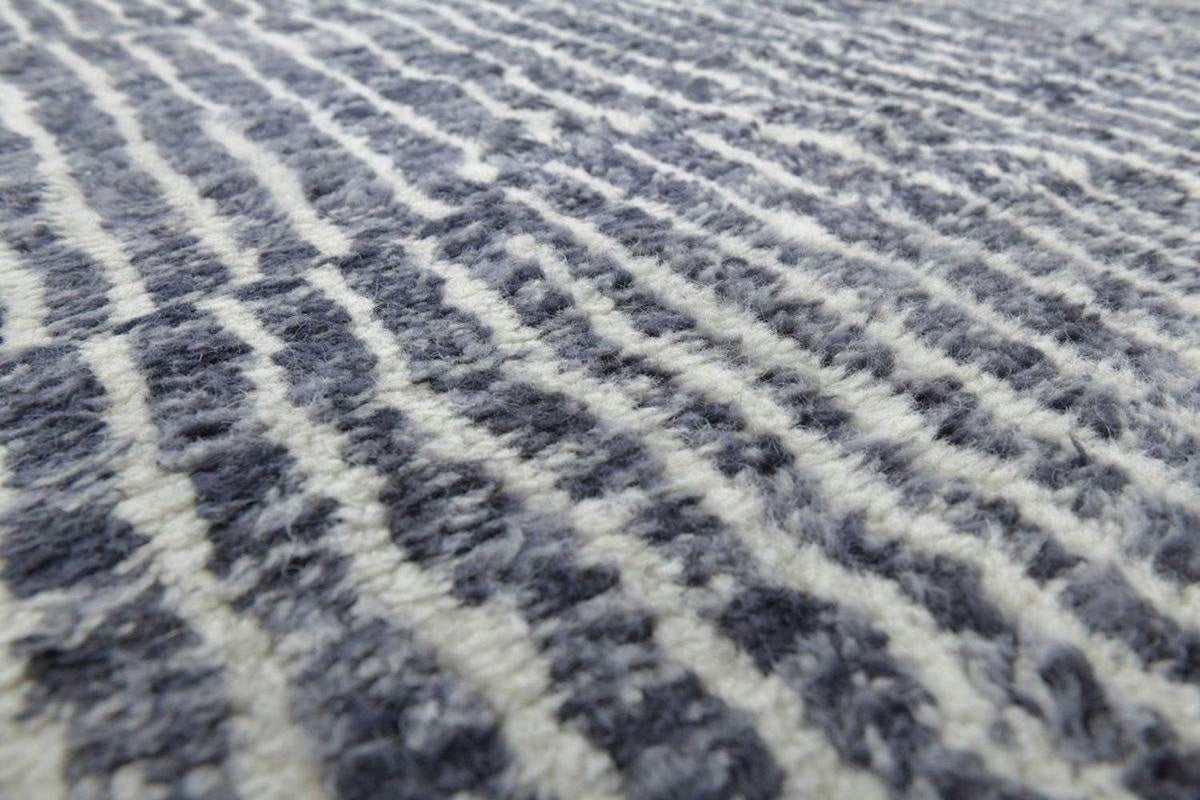 Close-up detail of the textured surface of a black tribal rug with a striped pattern.