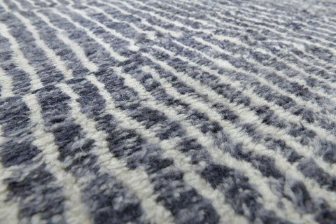 Close-up detail of the textured surface of a black tribal rug with a striped pattern.