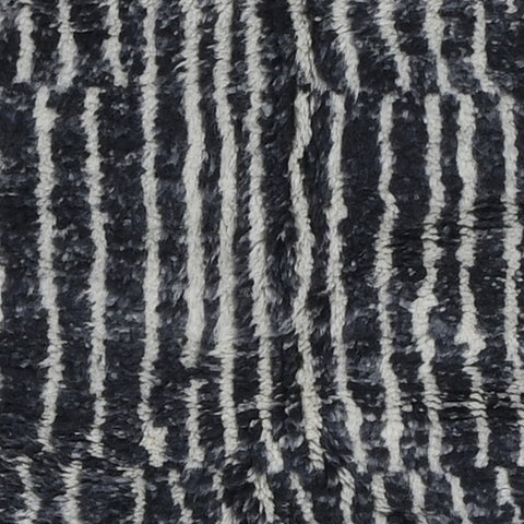 Close-up detail of a black and white rug featuring a striped pattern and fringe edges.