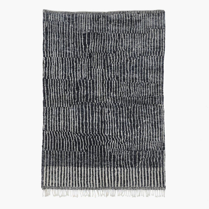 Front view of a black tribal rug featuring an abstract pattern and fringe edges.
