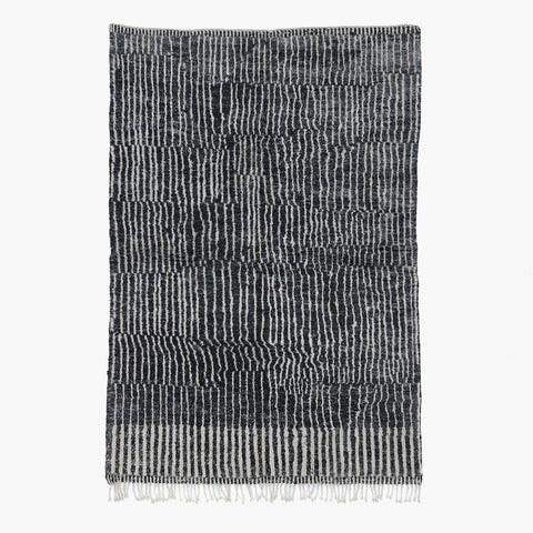 Front view of a black tribal rug featuring an abstract pattern and fringe edges.