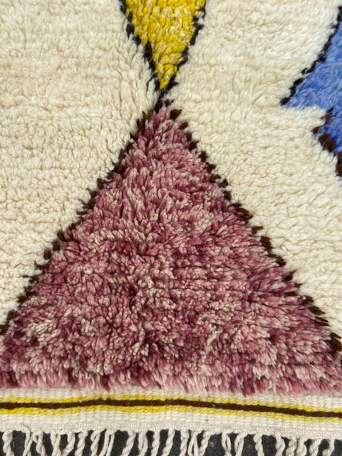 Close-up detail of colorful patches on a blue and yellow tribal Azilal rug.