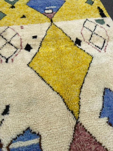 Close-up detail highlighting the geometric patterns on a blue and yellow tribal Azilal rug.