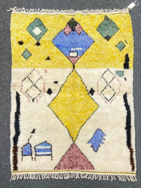 Front view of a blue and yellow tribal Azilal rug with geometric patterns and fringe edges.