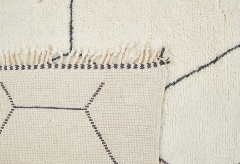 Close-up detail of the black and off-white Beni Ourain rug highlighting the stitching and texture.