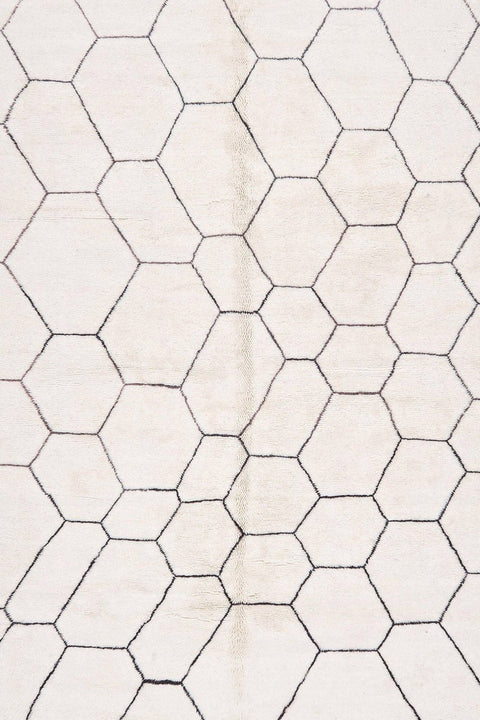 Close-up detail of the edge of the black and off-white Beni Ourain rug featuring fringe and stitching.