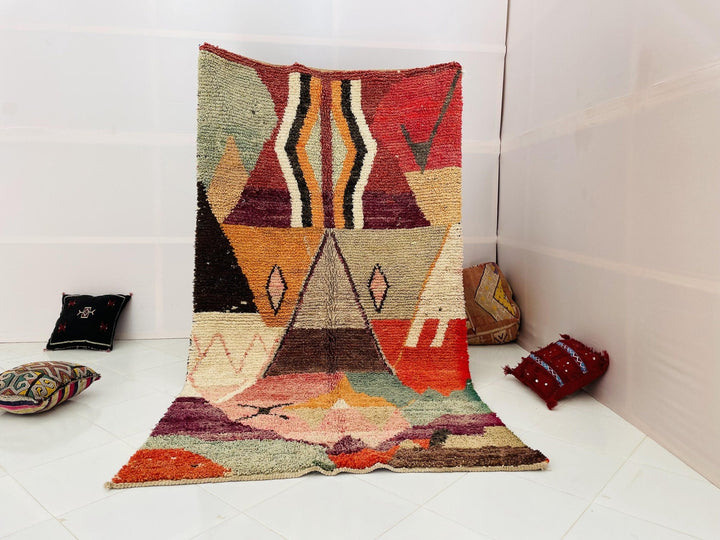 Lifestyle shot of a vintage Moroccan rug with geometric patterns in purple, pink, and green.