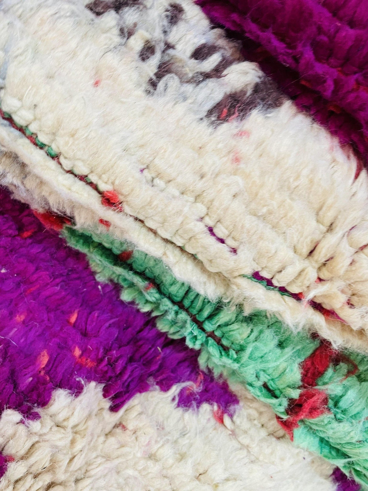 Close-up detail of the cream, green, and purple vintage Moroccan rug showcasing colorful patterns.