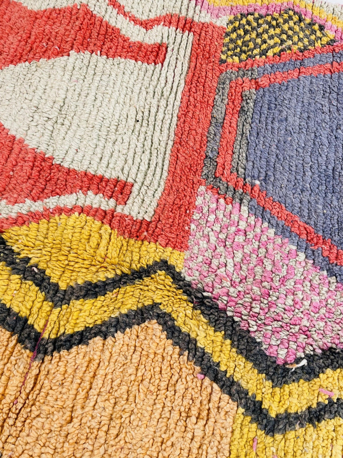 Close-up detail of the colorful pattern on the orange and pink abstract Moroccan rug featuring geometric shapes.