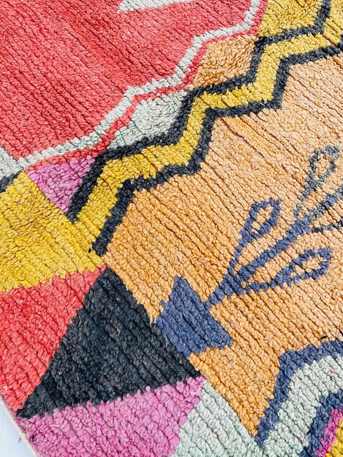 Close-up detail of the vibrant zigzag design on the orange and pink abstract Moroccan rug.
