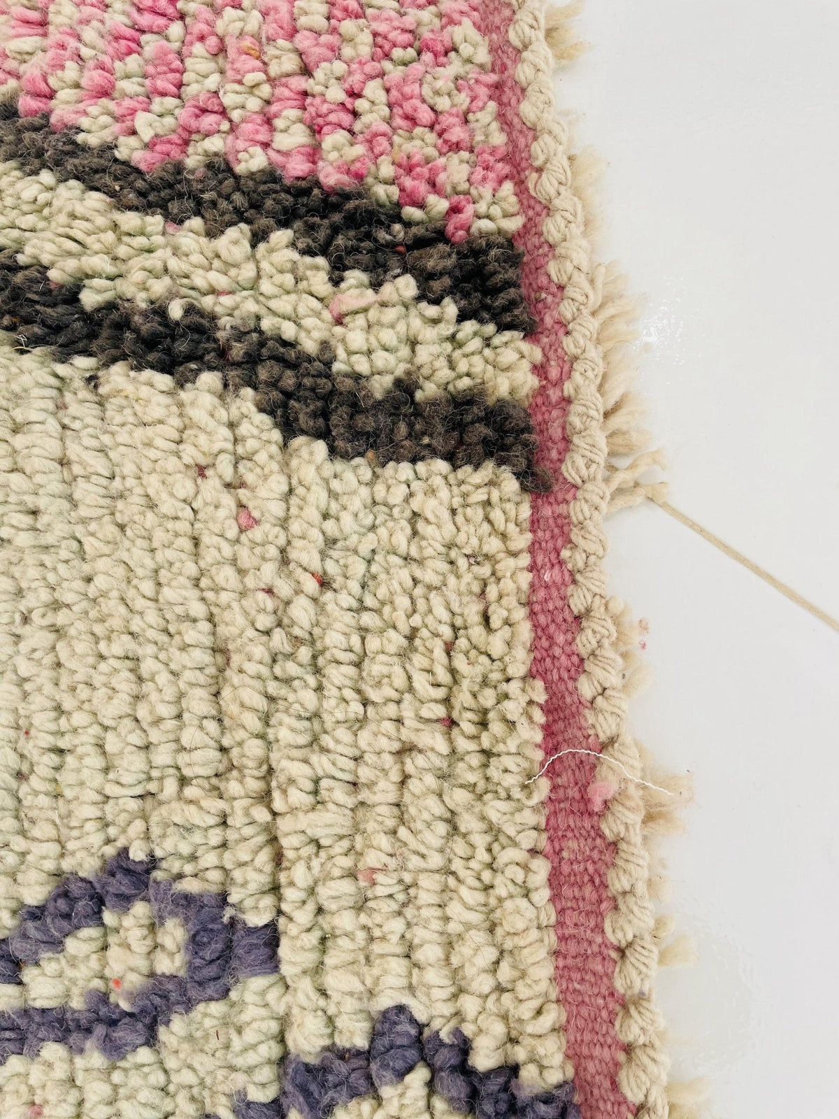 Detail close-up of the edge of the orange and pink abstract Moroccan rug with woven design.
