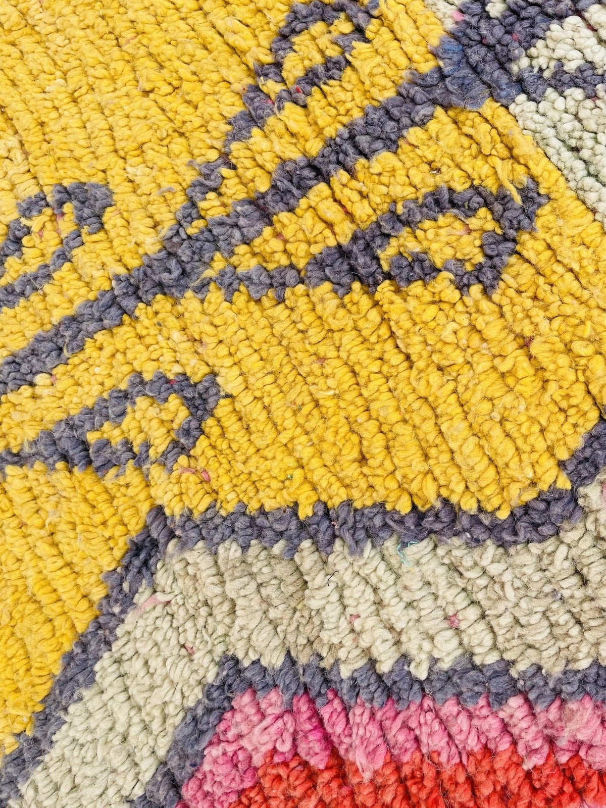 Close-up detail of the colorful pattern on the orange and pink abstract Moroccan rug.