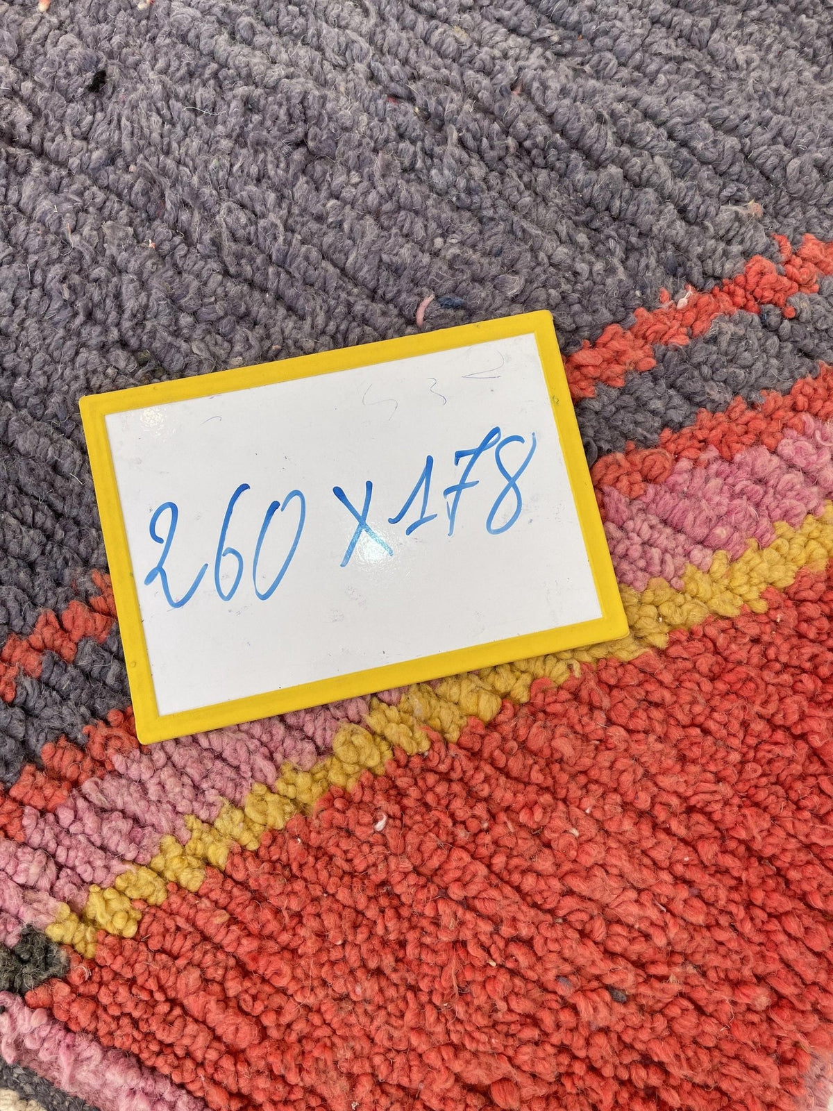 Detail shot of the label on the orange and pink abstract Moroccan rug showing a handwritten tag.