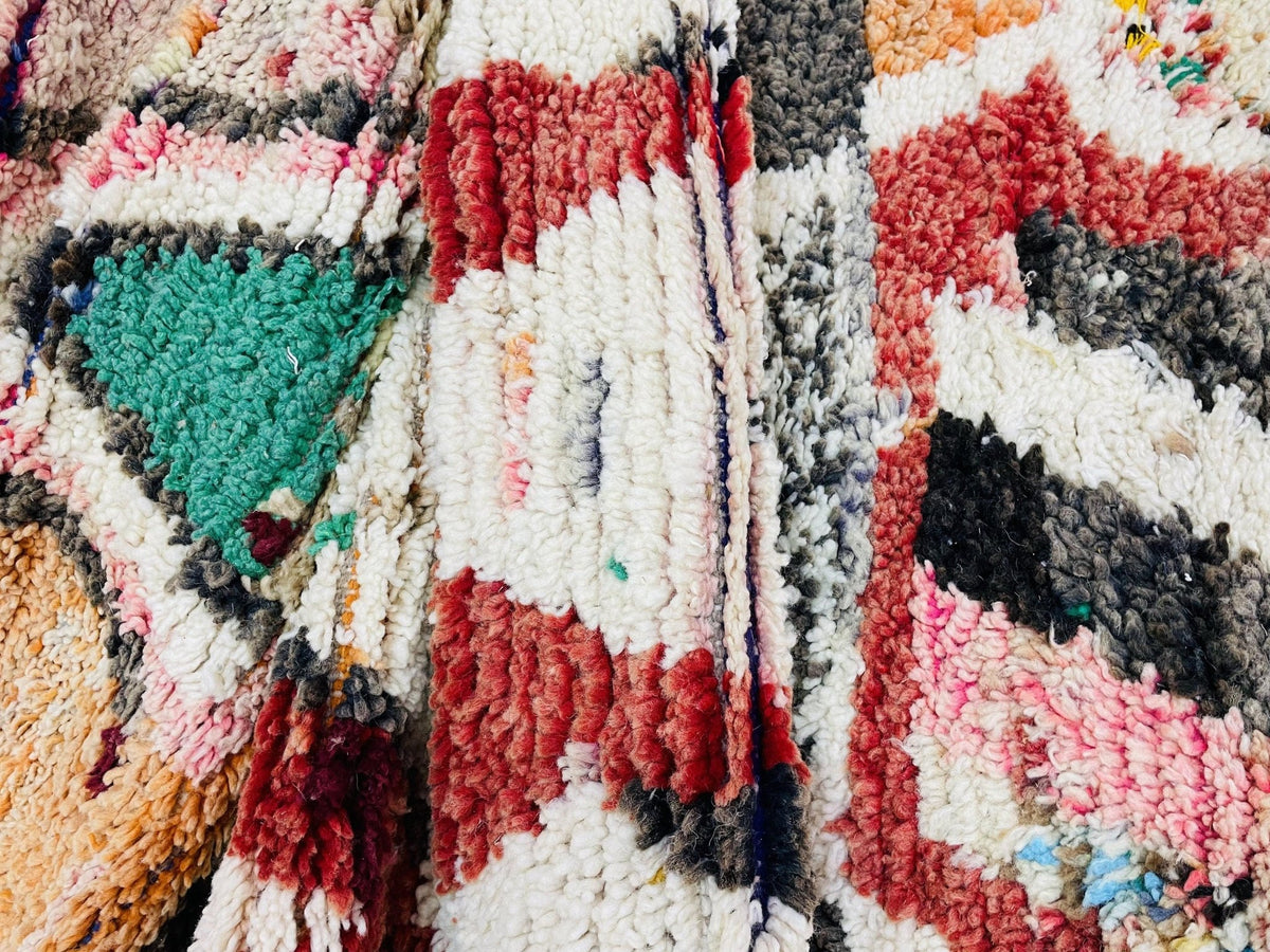 Detail close-up of a vintage Moroccan runner rug showcasing an abstract design with cream, red, blue, and black colors.