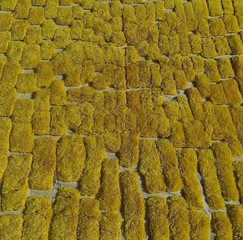 Close-up detail of the yellow Berber rug focusing on its soft texture and bright color.